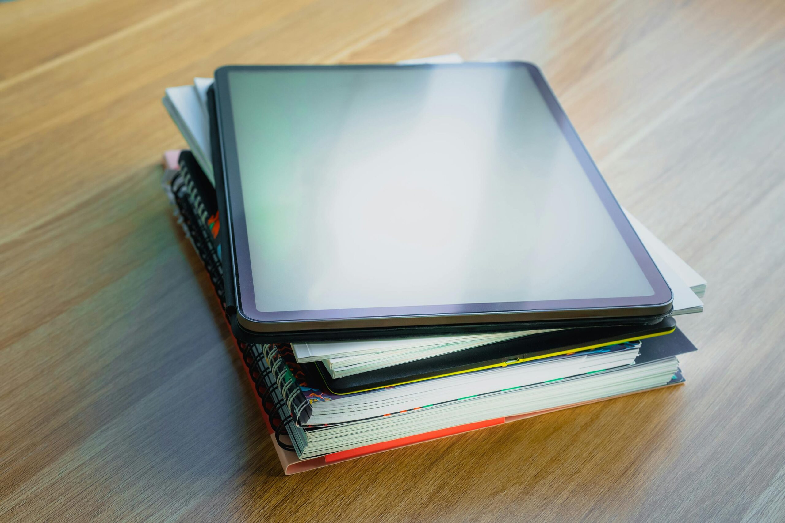 Digital tablet resting on top of a stack of books, depicting modern education and technology.